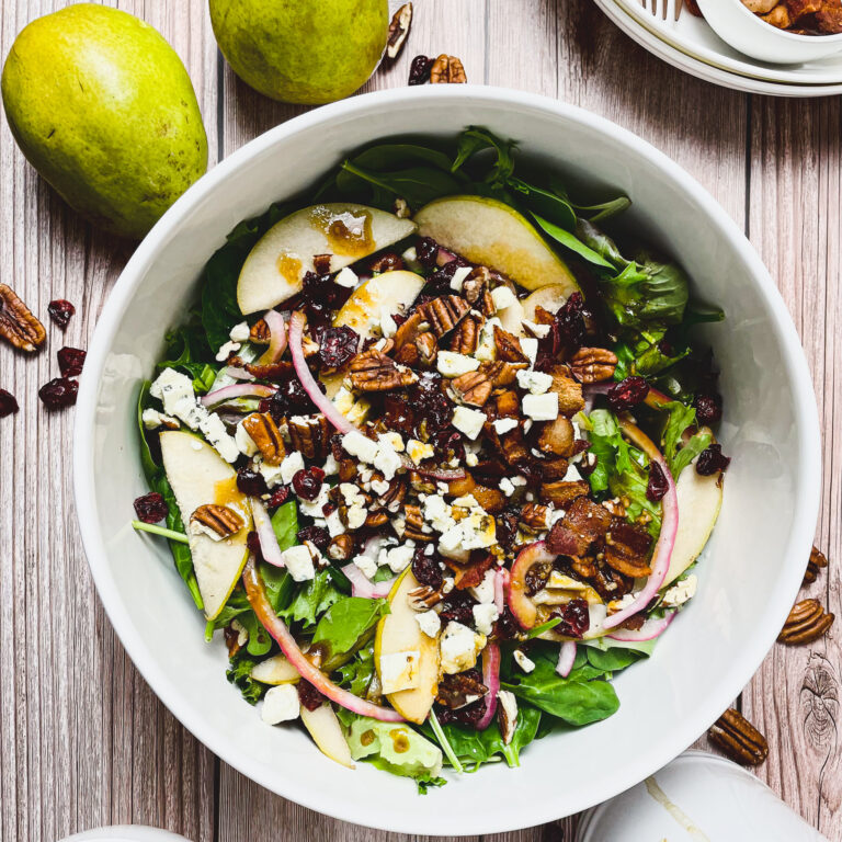 pear & gorgonzola salad with maple dressing in a white salad bowl on a picnic table
