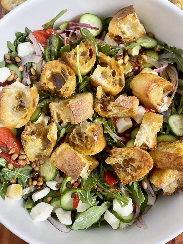 arugula salad with mozzarella cheese close up with homemade french bread croutons drizzle  with balsamic vinaigrette in white salad bowl
