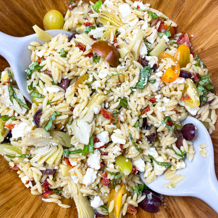 lemon orzo salad in a bamboo bowl with white porcelain serving spoons