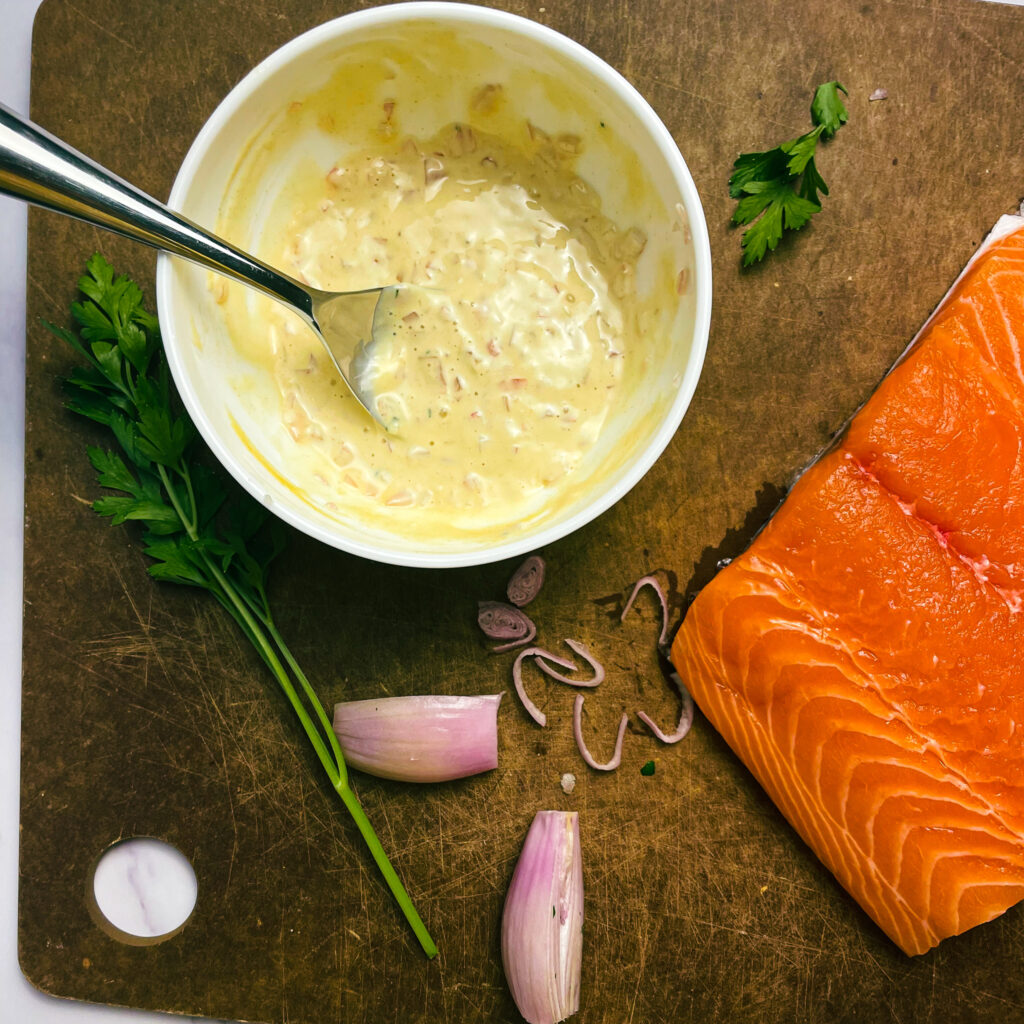maple dijon sauce in a white ramekin on a cutting board with a salmon filet