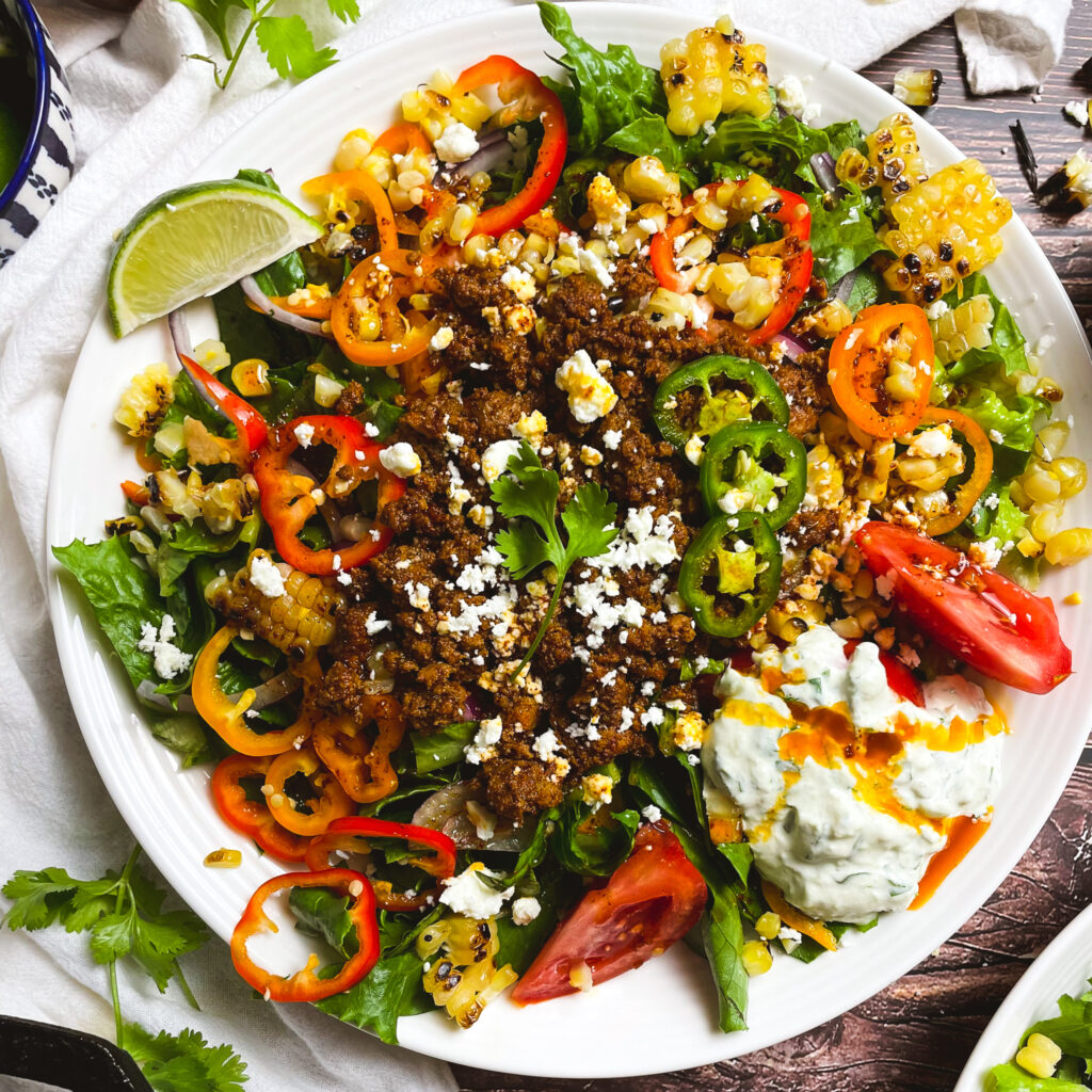 image of Mexican salad bowl in.a white Salad bowl with slice limed and cilantro on the table