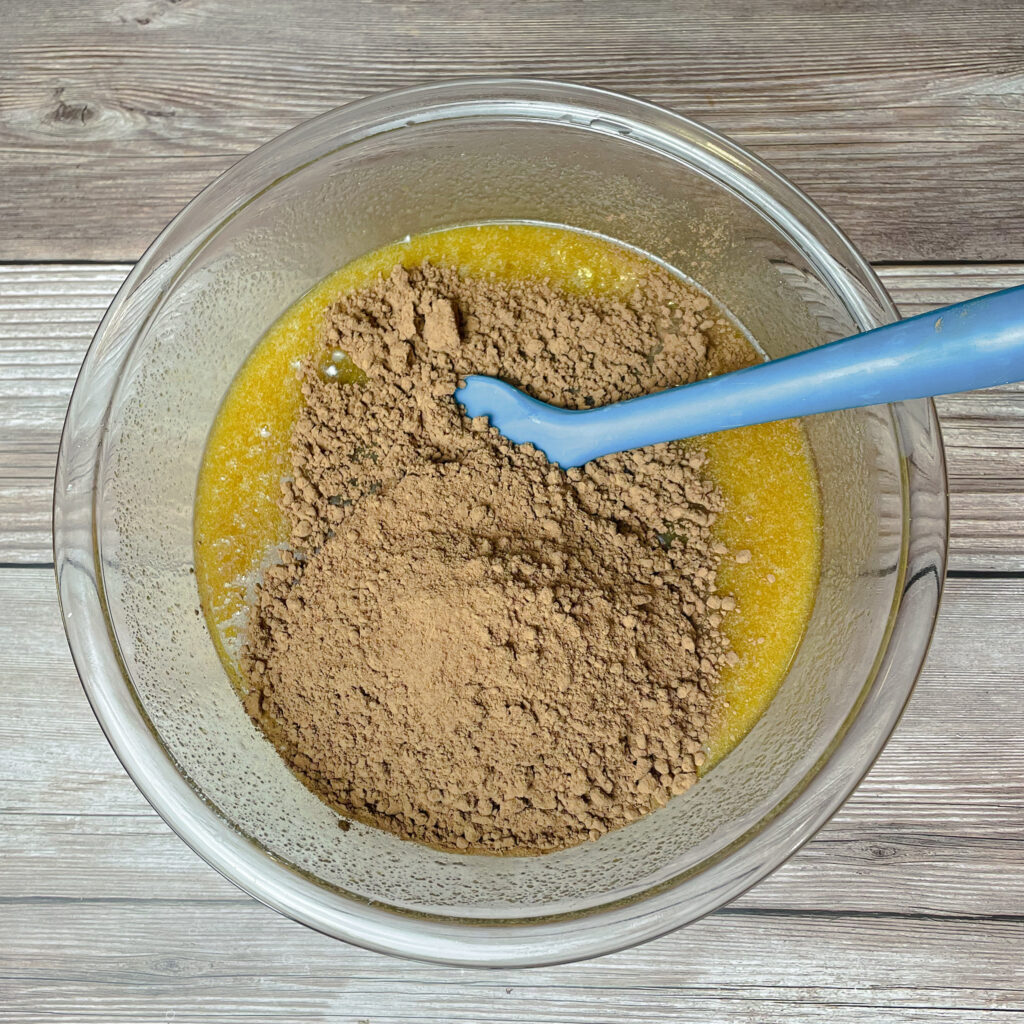 cocoa powder added to the brownie batter mixture with a rubber spatula to mix in.