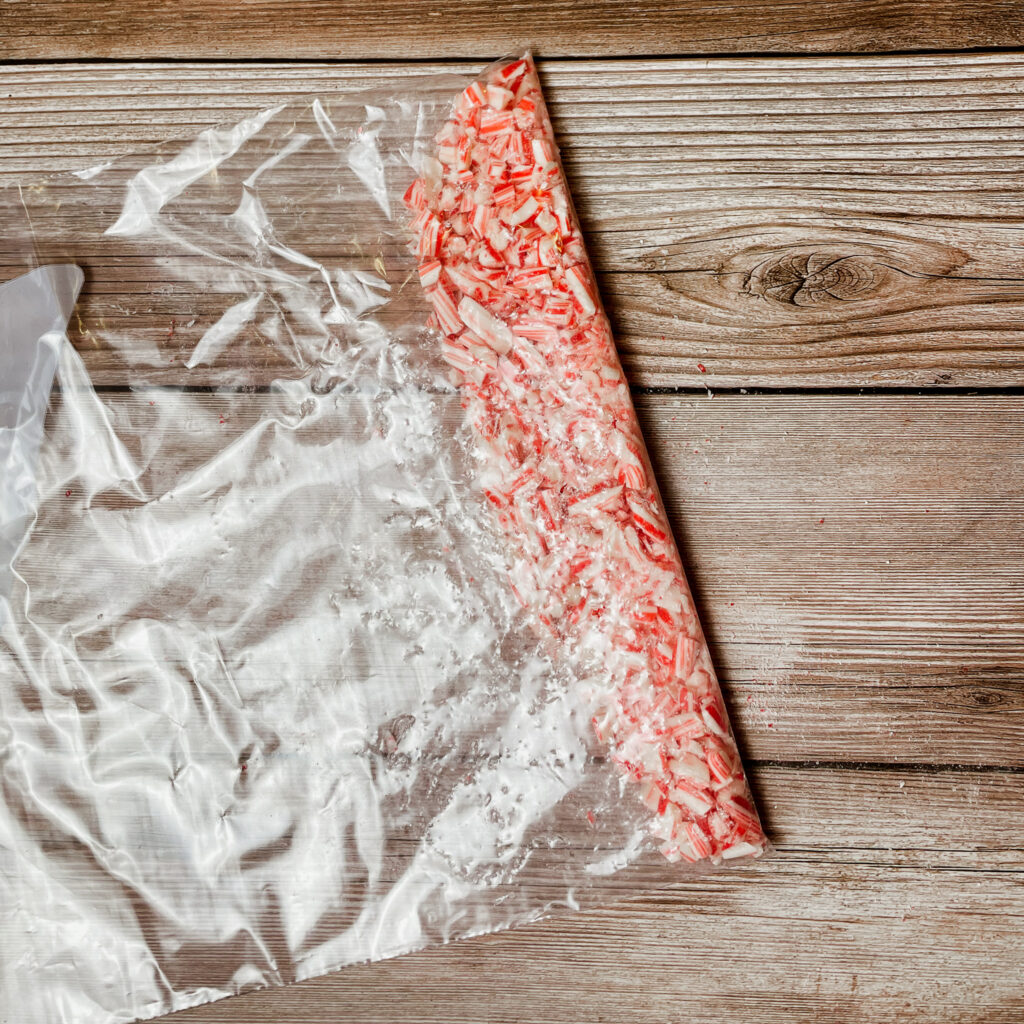 Crushed candy canes in a ziplock bag on wooden countertop.