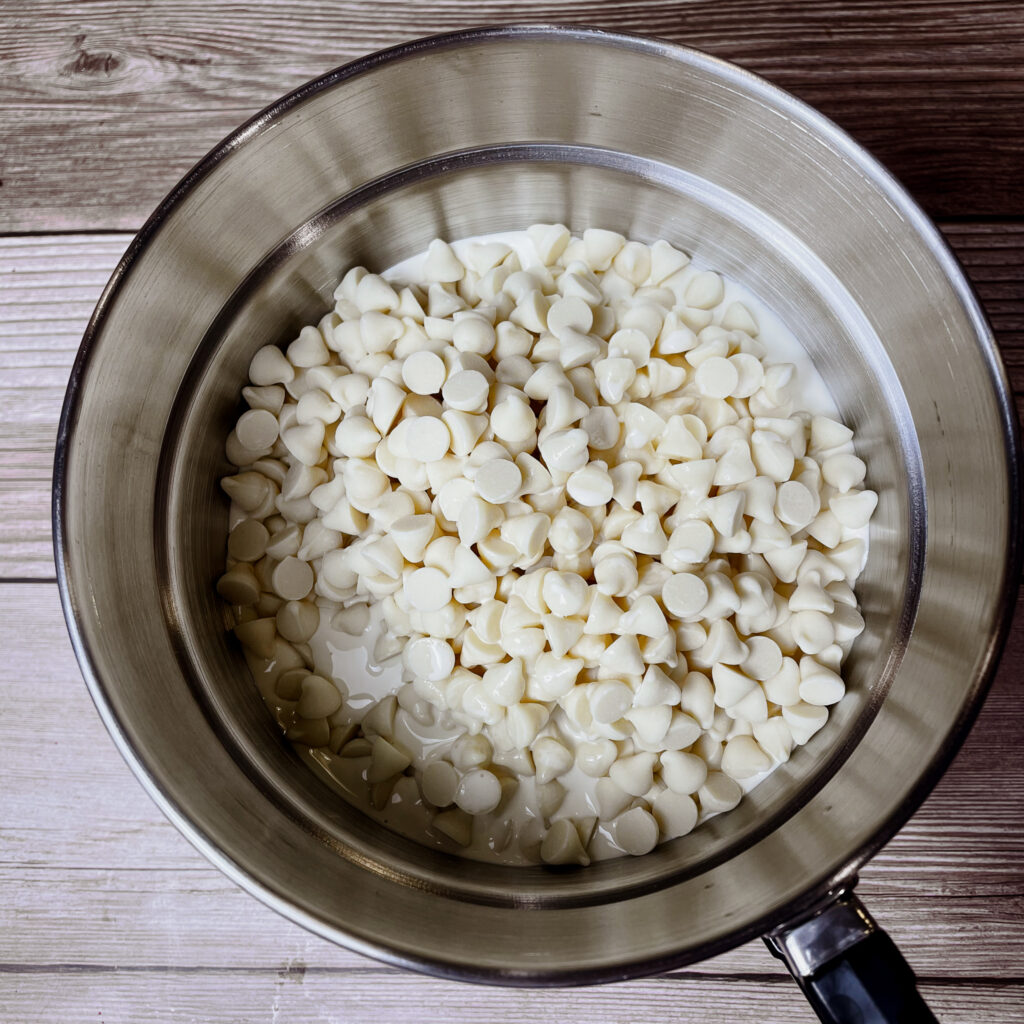 White chocolate chips, heavy cream and peppermint extract in the top pot of a double boiler.