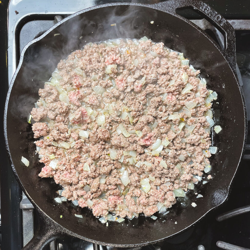 Sautéed onions and garlic with browned ground beef in a cast iron pan