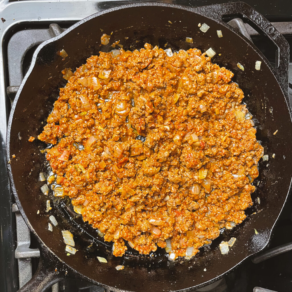 ground beef mixture in a cast iron pan with tomato paste and ketchup stirred in