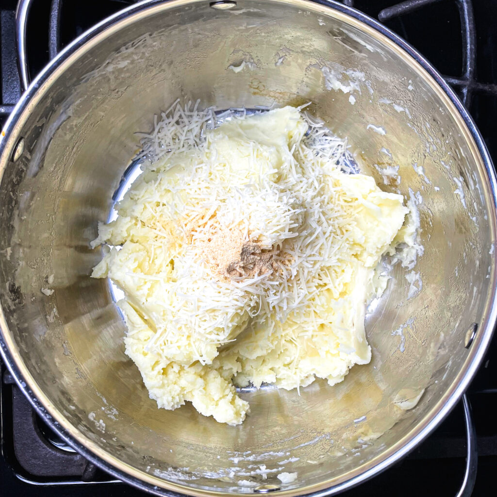 potatoes mashed in a pot with grated parmesan and garlic powder on top