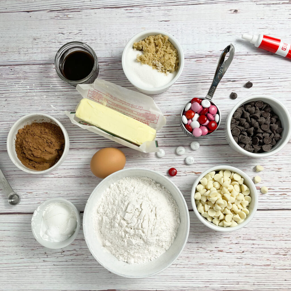 Ingredients for red velvet crumbl cookies measured out on a white wooden table