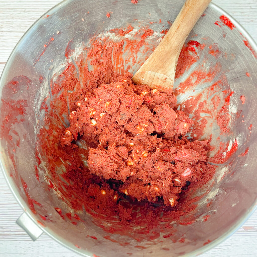 red velvet cookie dough mixed together in a mixing bowl with the chocolate chips folded in.