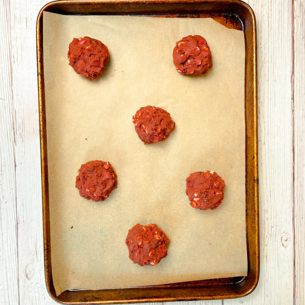 red velvet crumbl cookie dough balls on a baking sheet