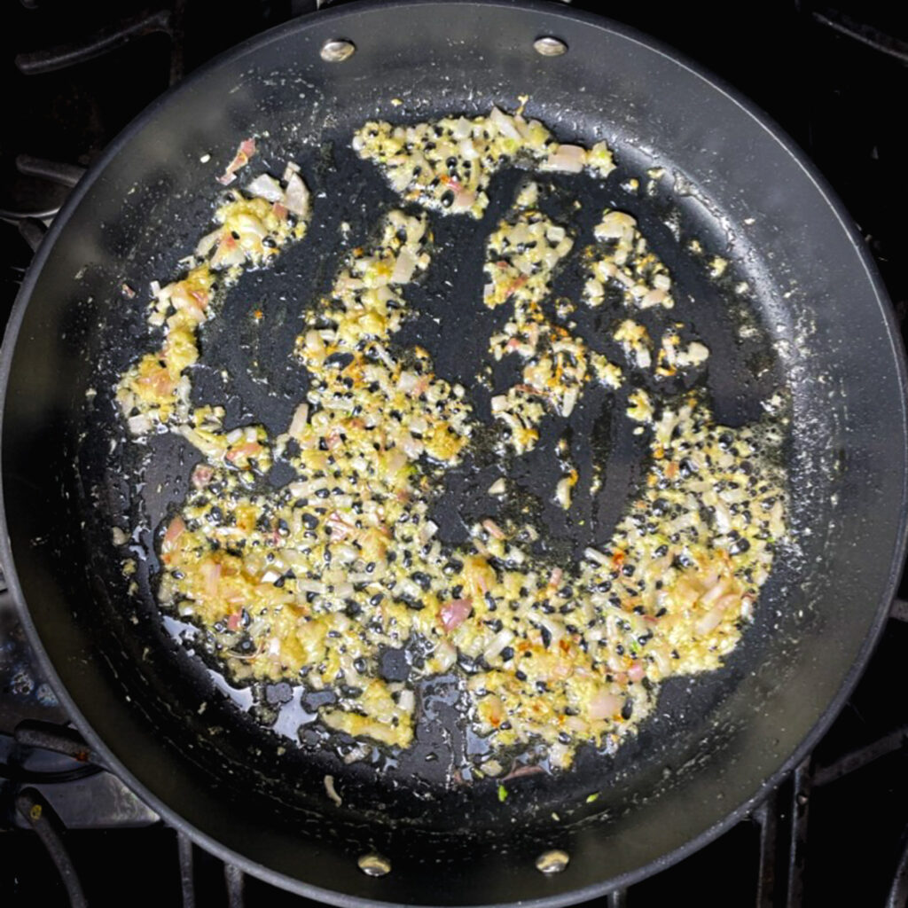 shallot and garlic cooking in a large fry pan.