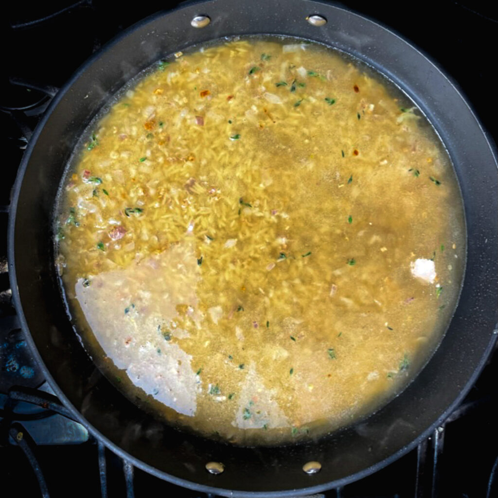 orzo in a large fry pan with chicken broth.