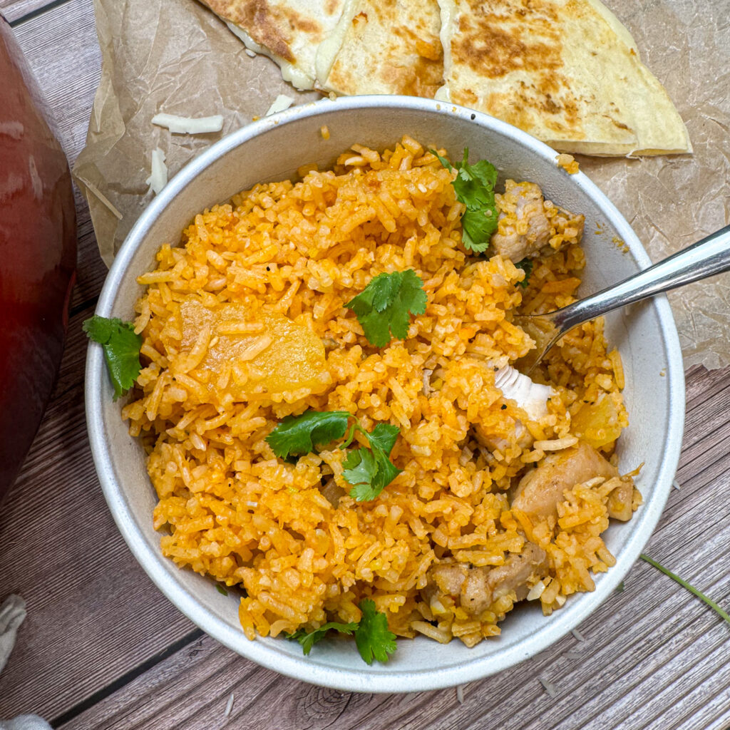chicken and rice in a white bowl with a fork, garnished with fresh cilantro