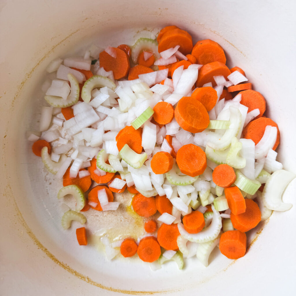Chopped carrots, celery, onion, and a garlic clove sizzling in the bottom of a Dutch oven, the start of a flavorful soup base.