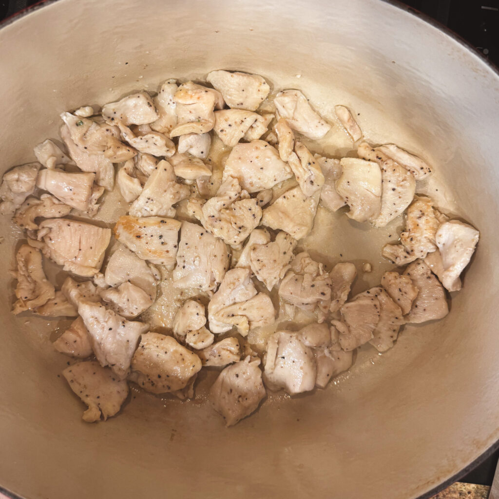 Golden seared chicken pieces in a Dutch oven — lightly browned and ready to soak up all that creamy curry flavor.