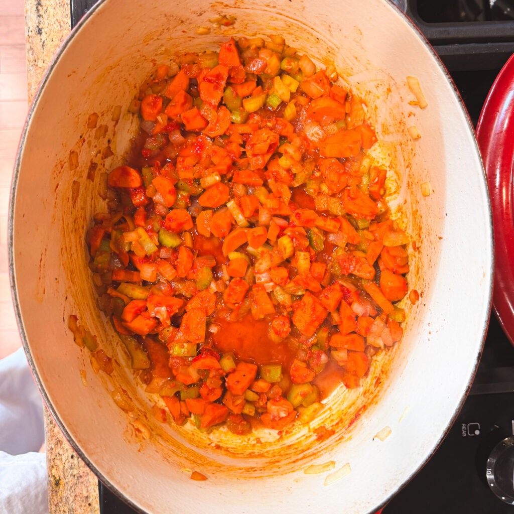 The veggies are coated in tomato paste and red wine, turning everything a rich brick-red color. The mixture looks glossy and caramelized as the tomato paste and red wine has cooked down and deepened in flavor.