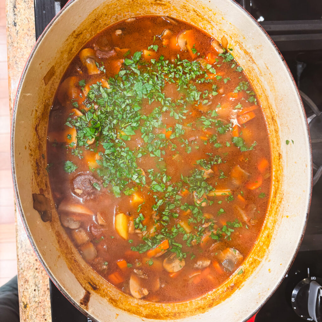 Freshly chopped parsley sprinkled over the top of the simmering beef barley mushroom soup, adding a pop of bright green to the hearty, rich broth.