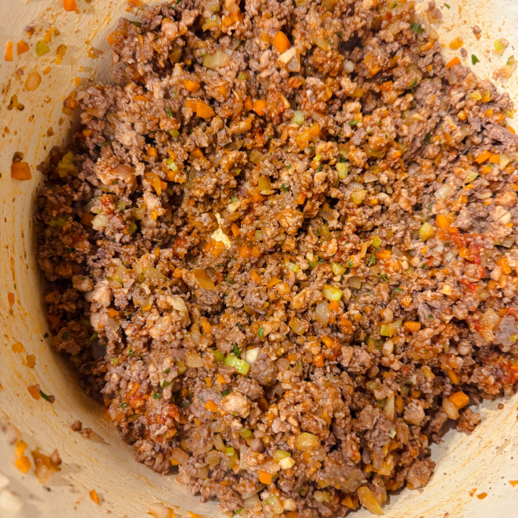 Tomato paste stirred into the meat mixture, deepening the color and richness of the bolognese.