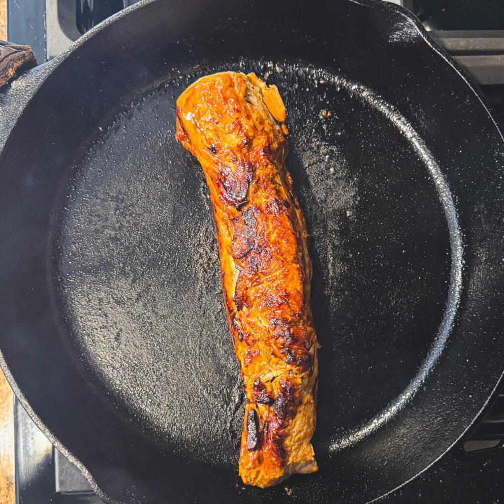 Pork tenderloin seared until deeply golden and caramelized in a cast iron skillet.