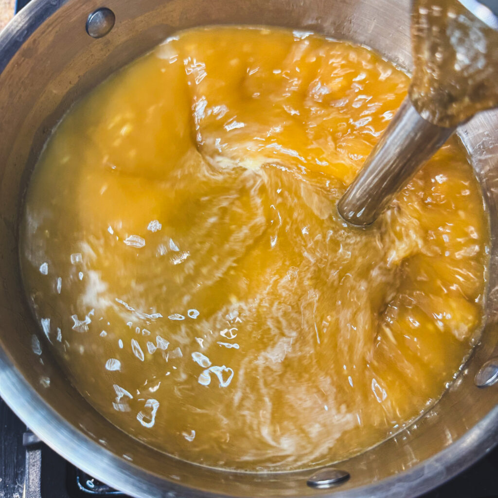 Immersion blender pureeing the ramen broth to create a smooth, rich base.