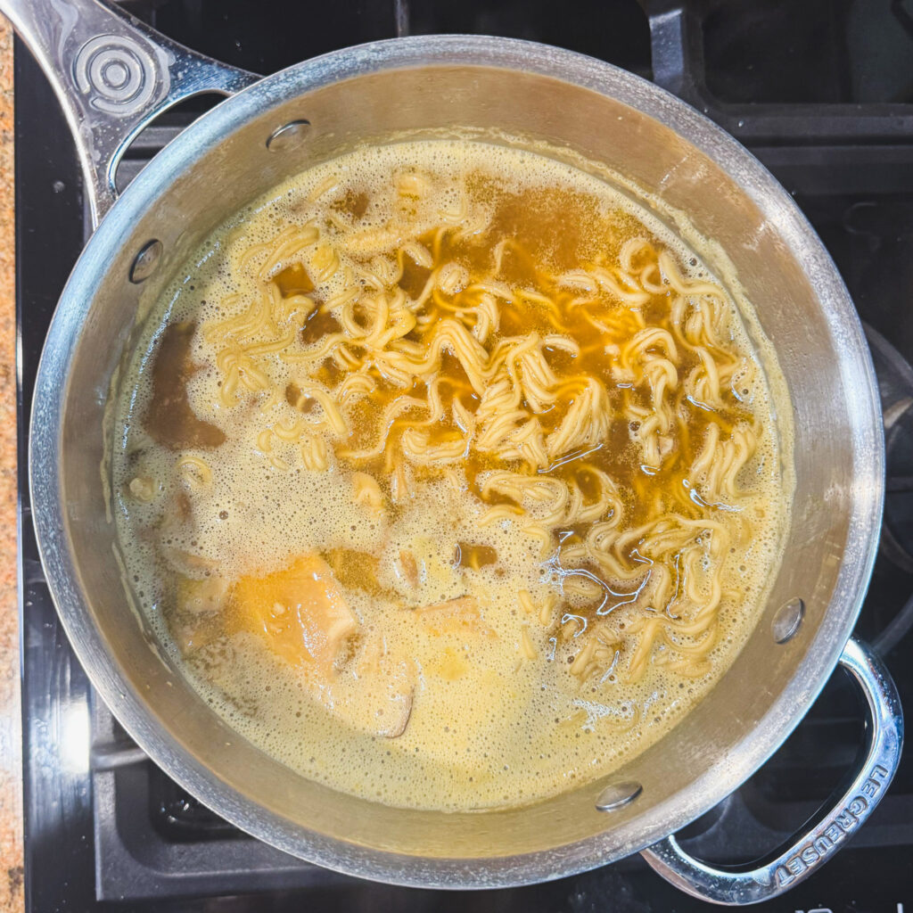 Ramen noodles cooking directly in the simmering broth.