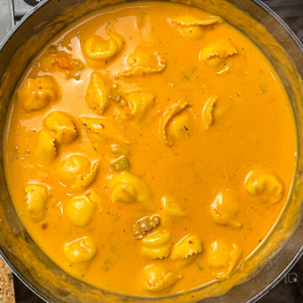 Cheese tortellini cooking in creamy Tuscan sausage soup.