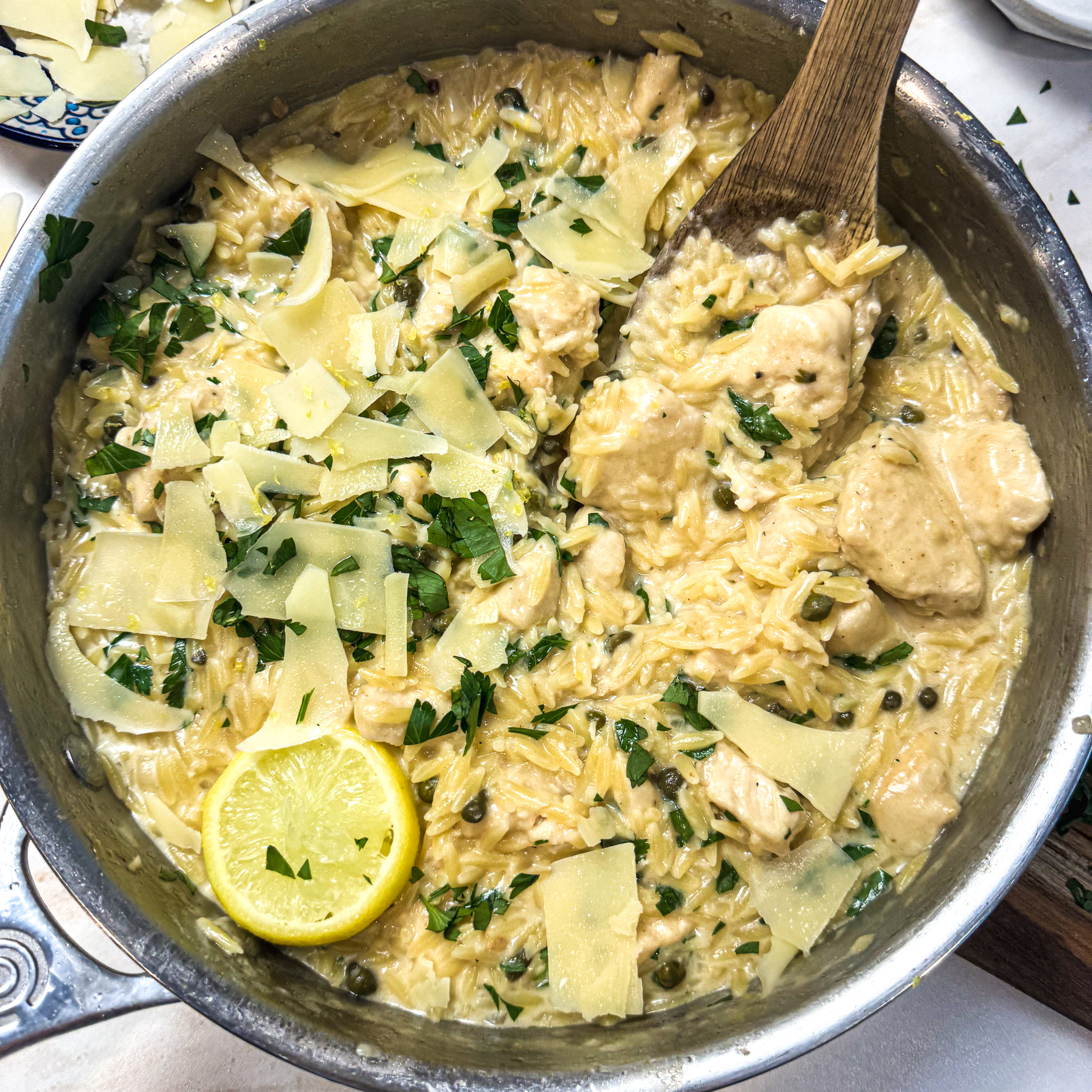 Close-up of creamy chicken piccata orzo with tender chicken, parmesan, capers, and fresh parsley.