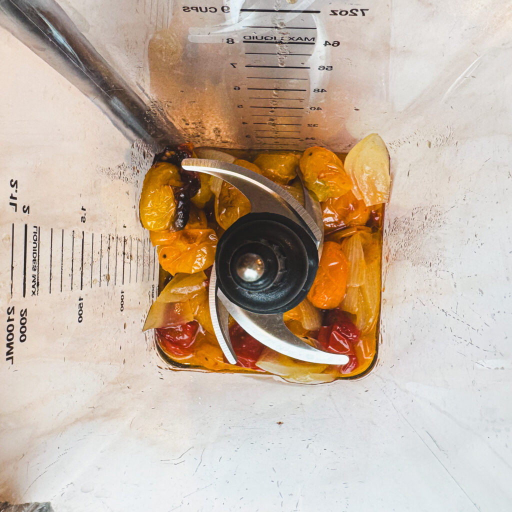Roasted tomatoes, onion, and garlic added to a blender to make a smooth and creamy roasted tomato sauce.