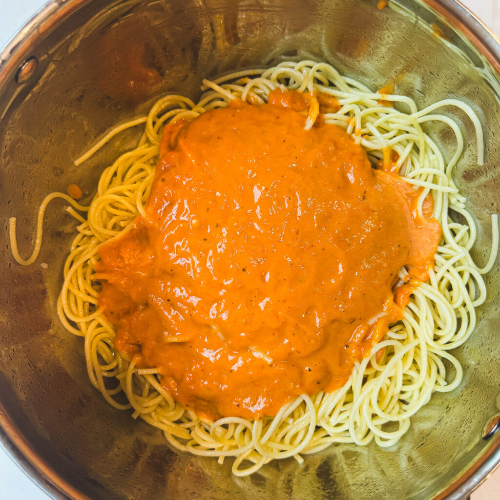 Freshly cooked spaghetti topped with creamy roasted tomato sauce before tossing together.