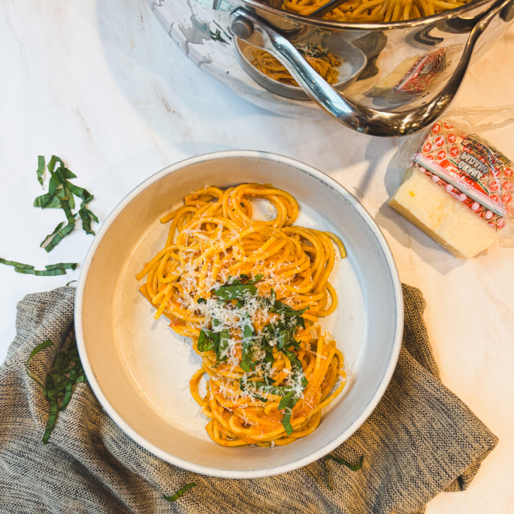 Spaghetti coated in homemade roasted tomato sauce before serving with fresh basil and Parmesan cheese.