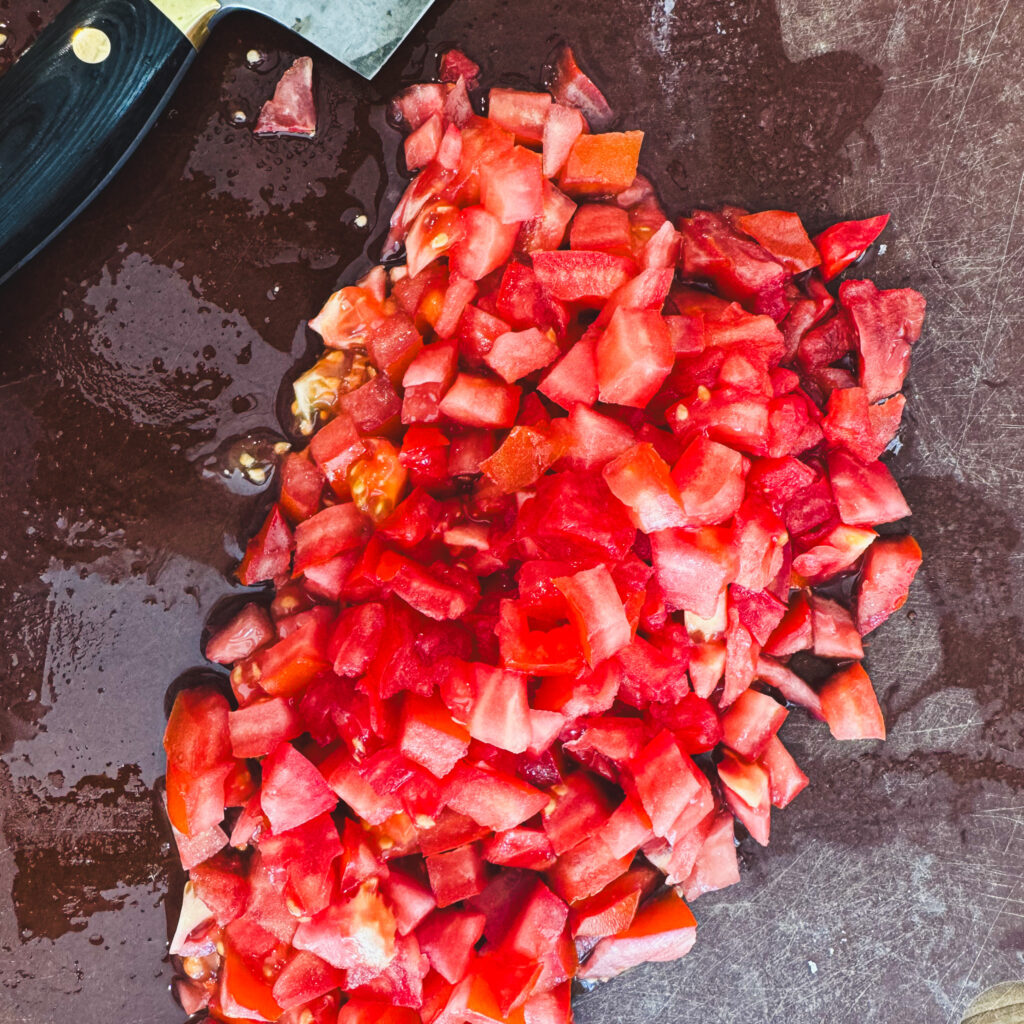 Fresh ripe tomatoes diced on a cutting board for homemade bruschetta.