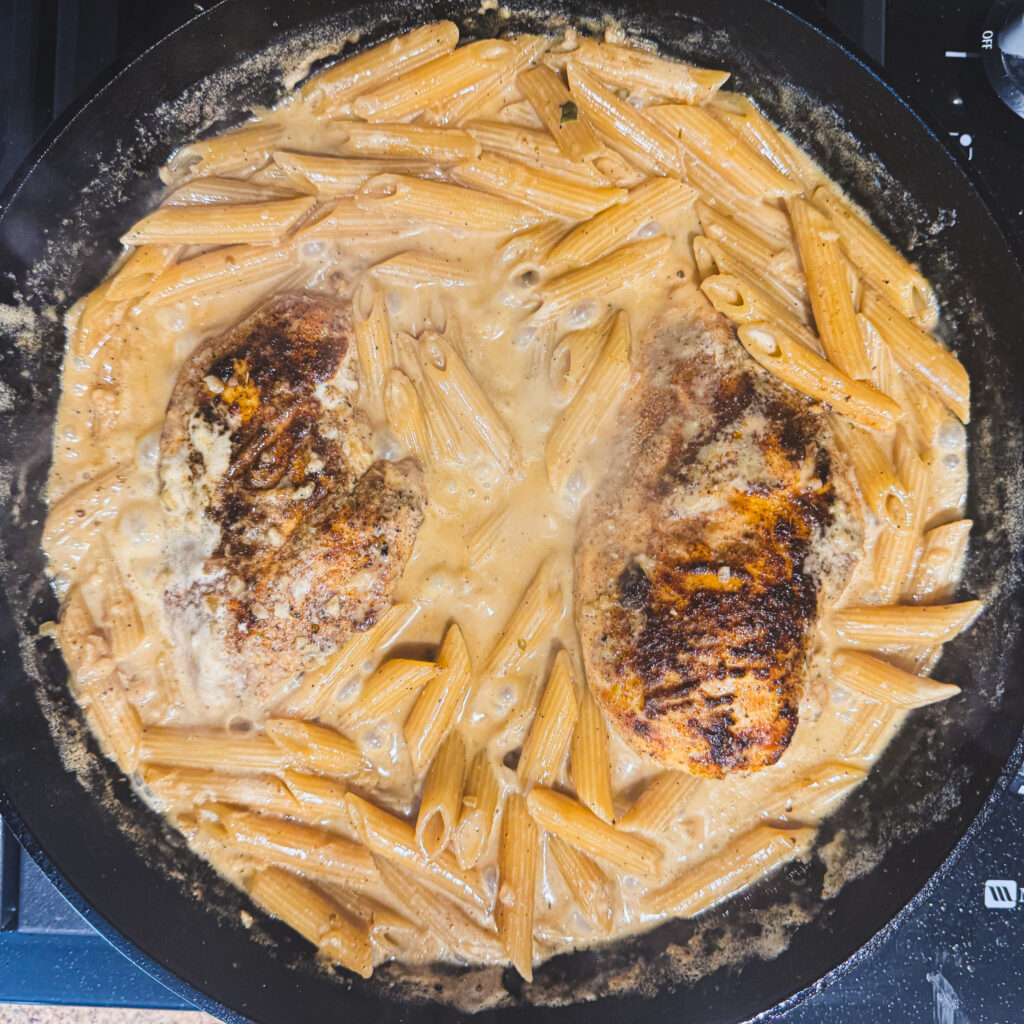 Golden seared chicken breasts returned to the creamy pasta to finish cooking.