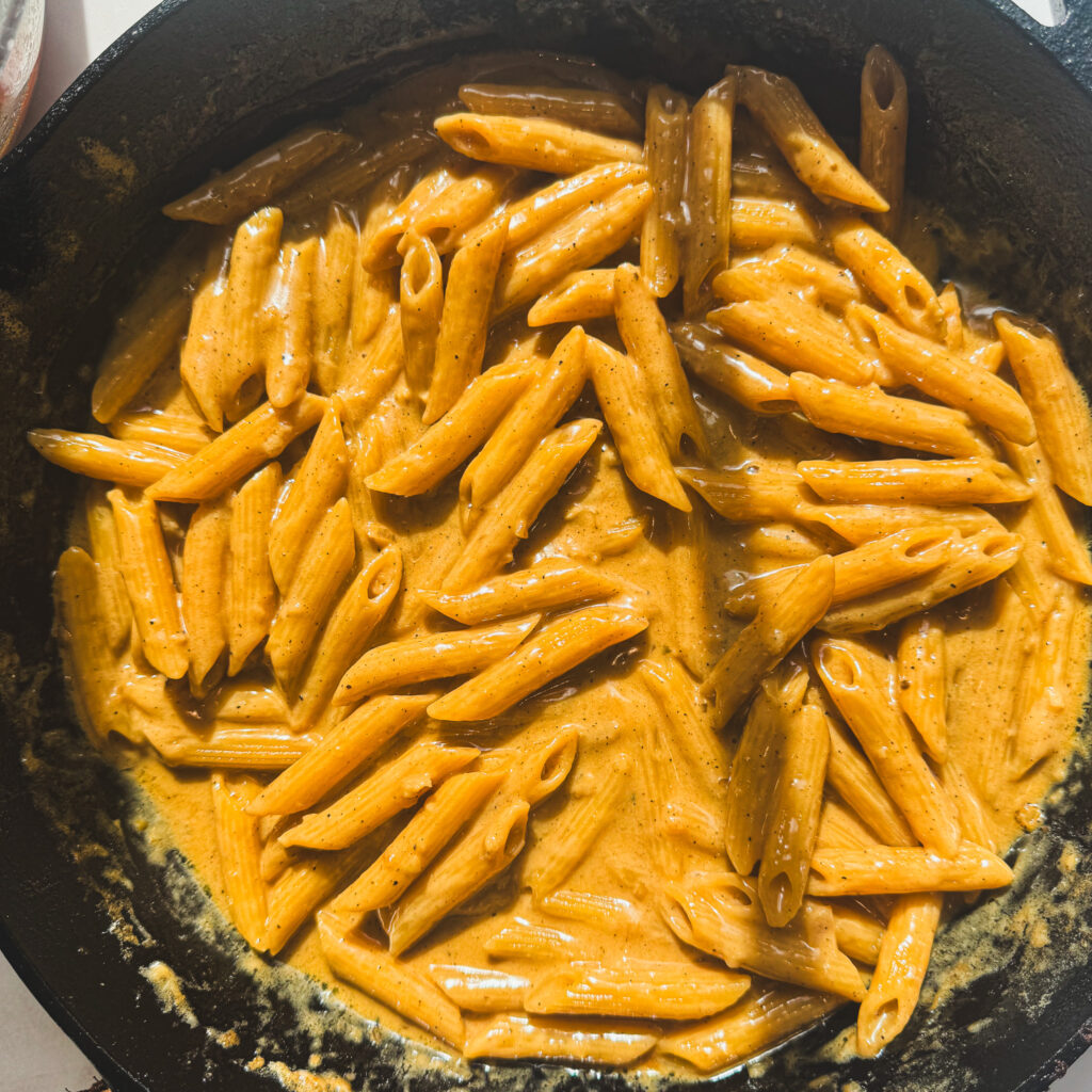 Creamy Parmesan penne pasta stirred until smooth and coated in sauce.