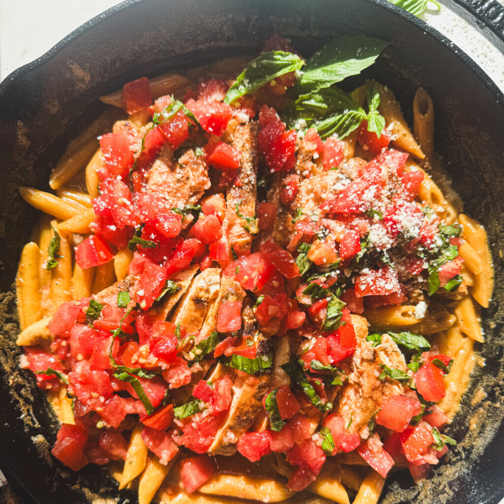 Creamy bruschetta chicken pasta topped with fresh tomato bruschetta, basil, and grated Parmesan.