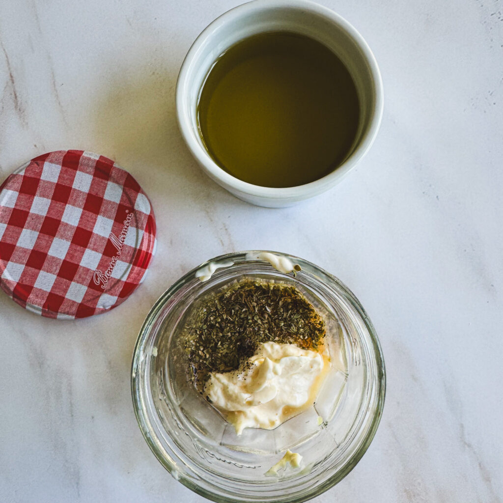 Homemade creamy Italian dressing ingredients added to a glass jar before mixing.