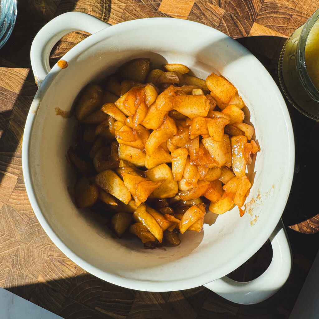Cinnamon apples cooked with butter and brown sugar for a gooey apple fritter skillet cake filling.
