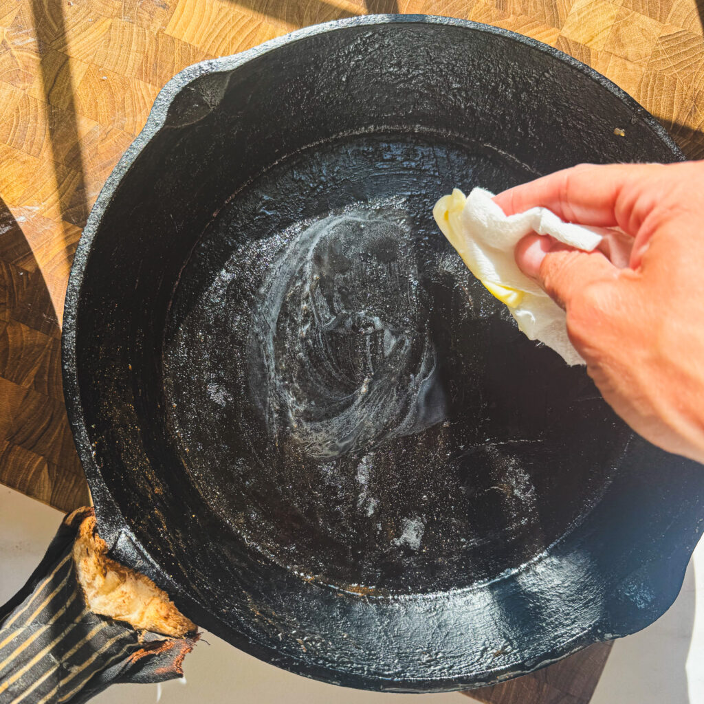 Preparing skillet: Buttering a cast iron skillet before adding batter for an easy cast iron apple cake.