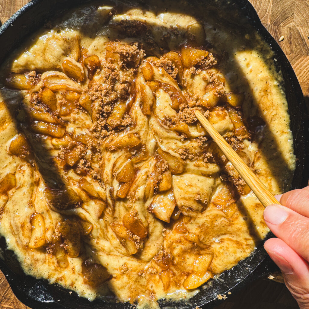 Swirling: Swirling cinnamon apples and brown sugar into apple fritter skillet cake before baking.