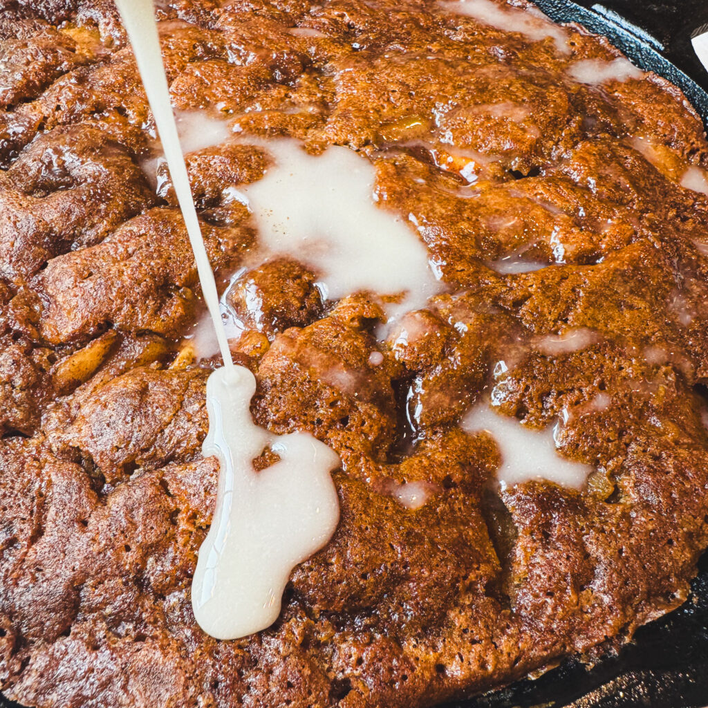 Glaze pour: Vanilla glaze poured over warm apple fritter skillet cake with cinnamon apples and brown butter.