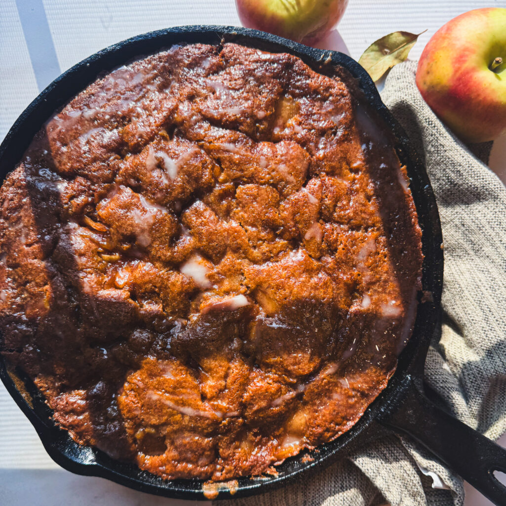Styled skillet: Homemade apple fritter skillet cake with cinnamon apples and vanilla glaze, an easy fall apple dessert.