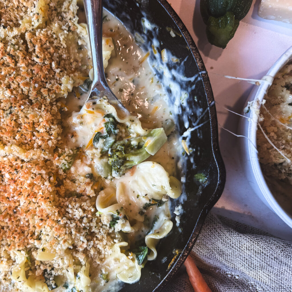 Spoon serving creamy skillet white lasagna primavera with broccoli and crispy breadcrumbs.