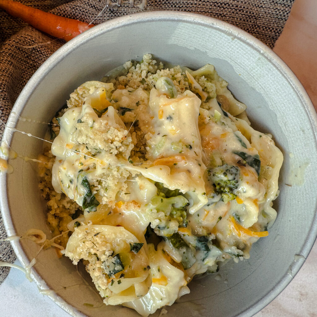 Bowl of creamy white lasagna primavera with broccoli, spinach, carrots and crispy breadcrumbs