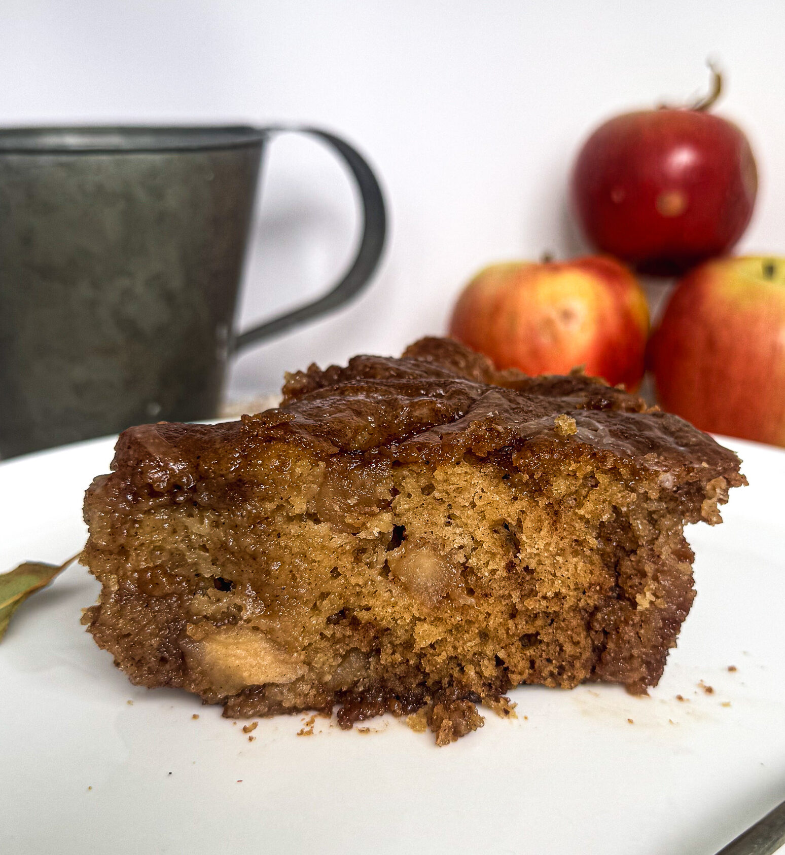 Plated slice #1: Slice of brown butter apple fritter cake with gooey cinnamon apple layers and vanilla glaze.