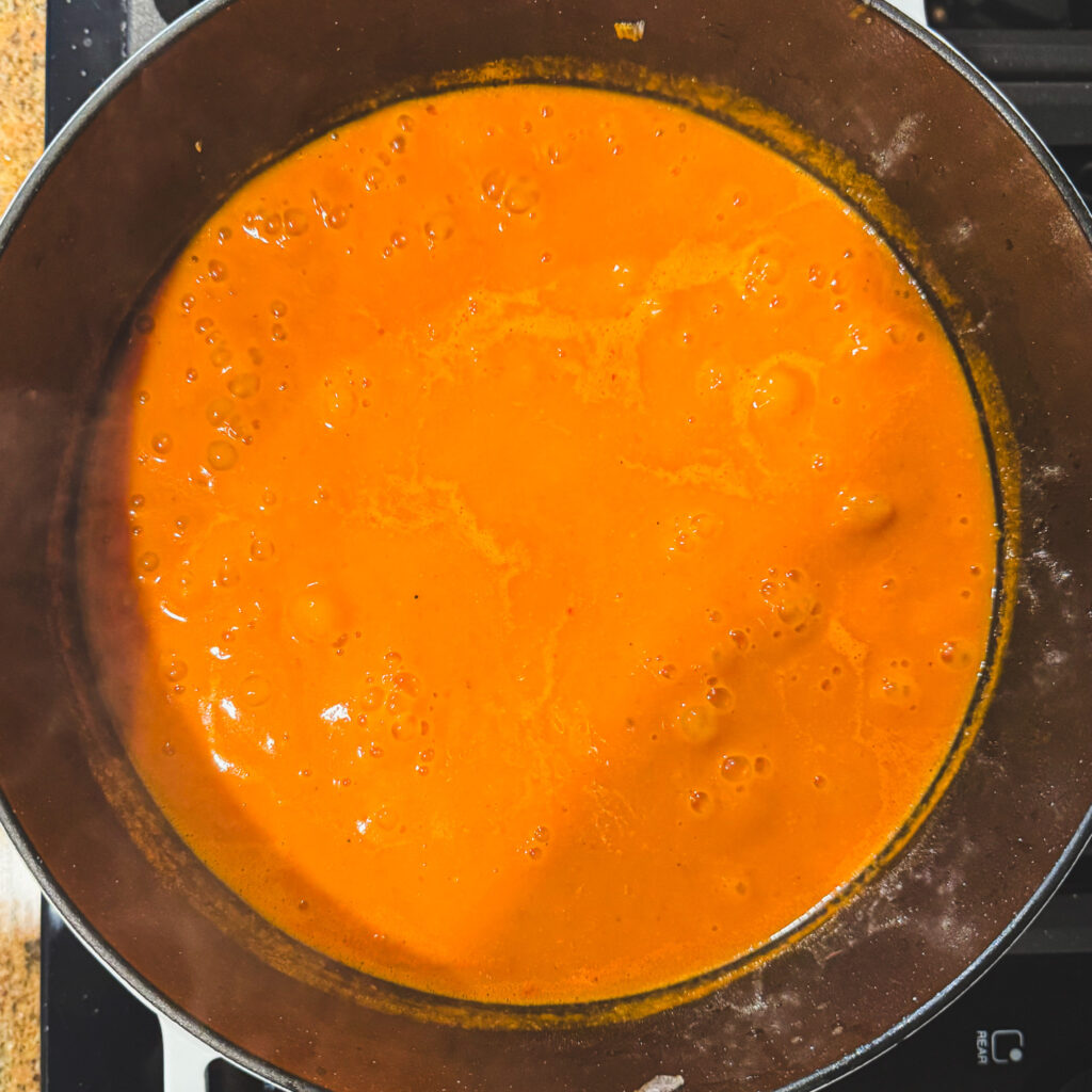 Simmering soup: Smooth, creamy tomato soup simmering in a Dutch oven after blending the tomatoes, onions, and garlic.