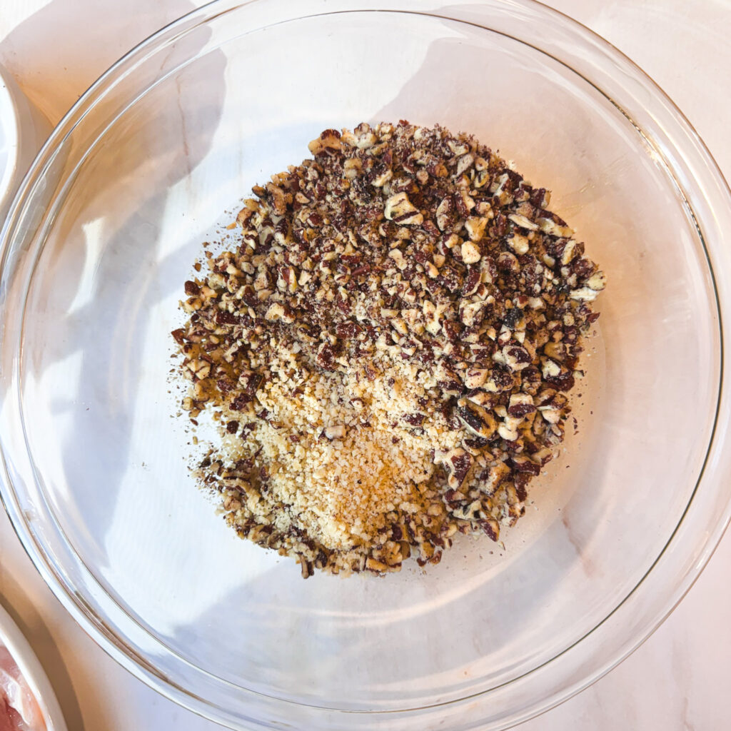 Finely chopped pecans and panko breadcrumbs added to a glass mixing bowl.