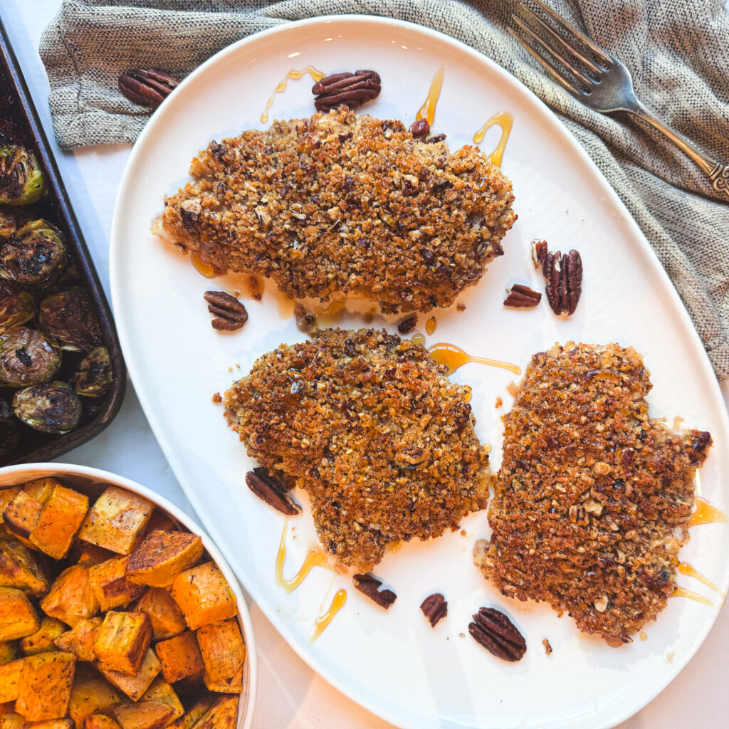 Honey-drizzled pecan-crusted chicken served with roasted sweet potatoes and Brussels sprouts.