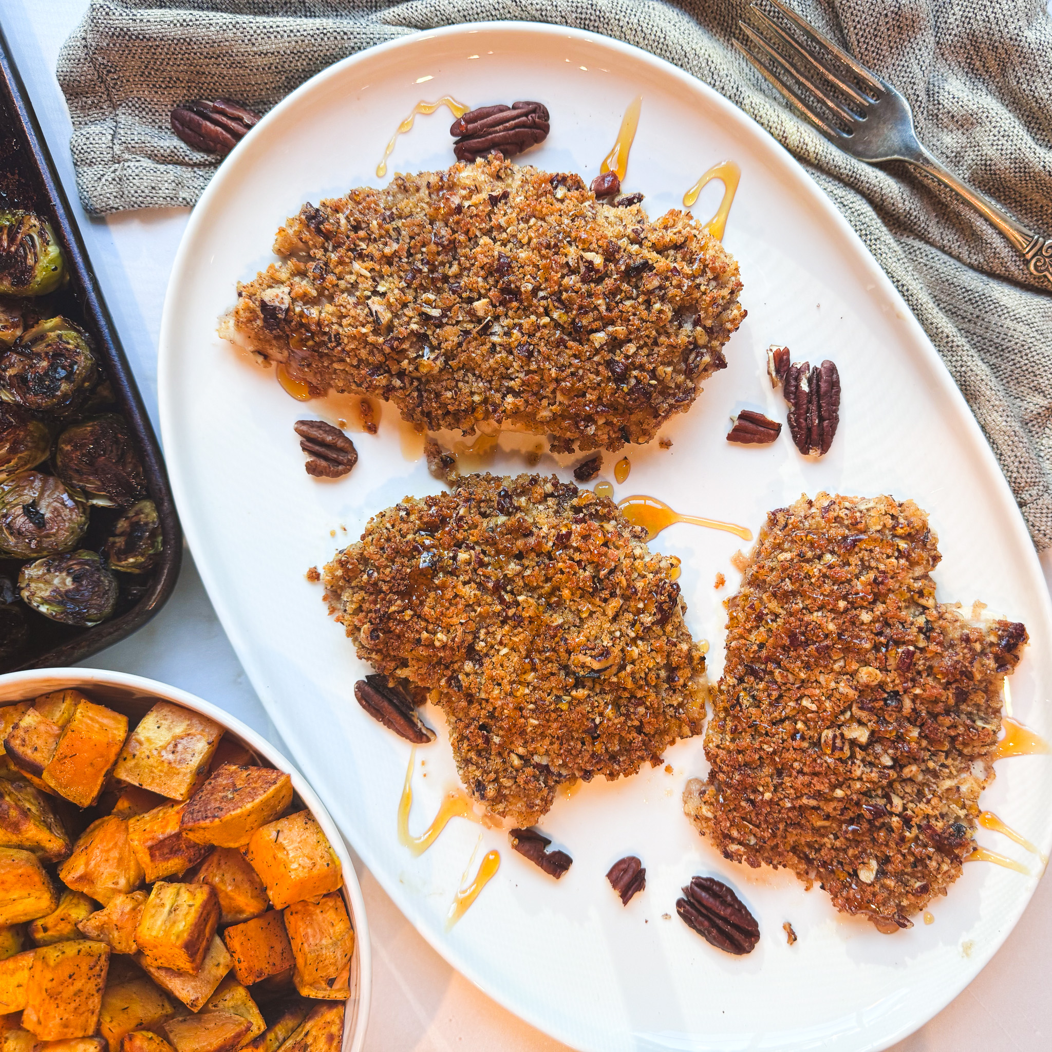 Honey-drizzled pecan-crusted chicken served with roasted sweet potatoes and Brussels sprouts.