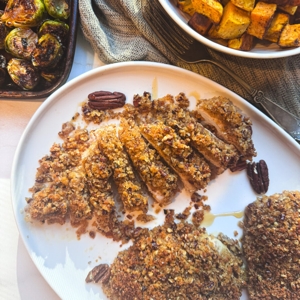 Sliced pecan-crusted chicken showing the juicy white meat beneath the crunchy topping.