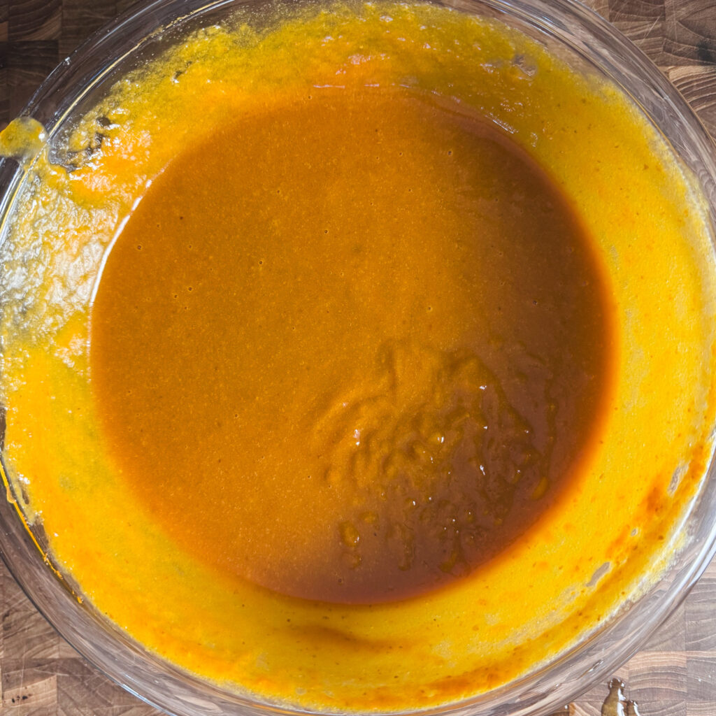 Pumpkin puree, brown sugar, avocado oil, eggs, and vanilla mixed together in a glass bowl for pumpkin whoopie pie batter.