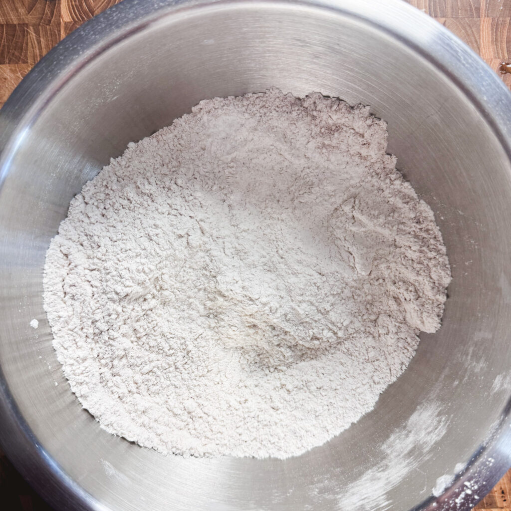 All-purpose flour, pumpkin pie spice, cinnamon, baking powder, baking soda, and salt whisked together in a mixing bowl.